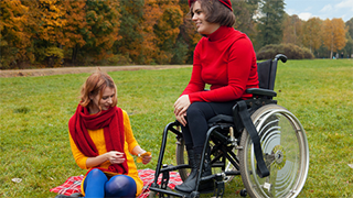 Niepełnosprawna kobieta na wózku inwalidzkim z towarzyszącą osobą